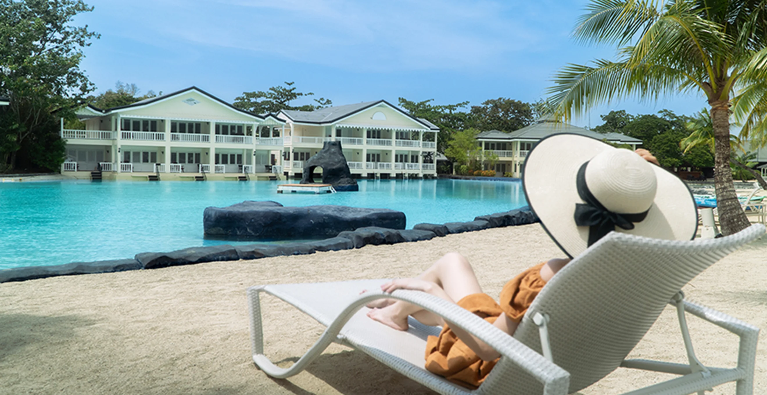 Guest relaxing on a lounger beside Plantation Bay's saltwater lagoon