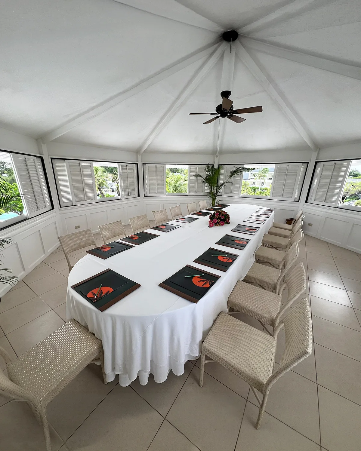Bright function pavilion on the top floor of the Alien building, windows open to the breeze, an oval conference table under a high white ceiling
