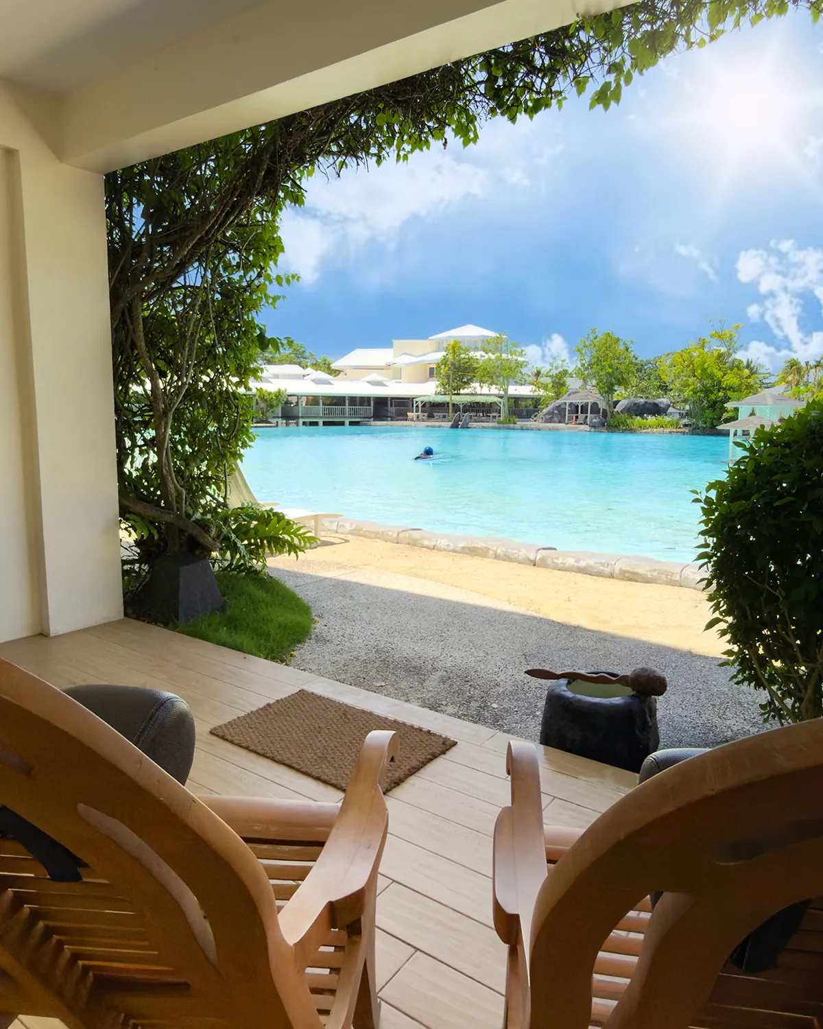 Balcony with butaka chairs under a bright blue sky, the lagoon just beyond