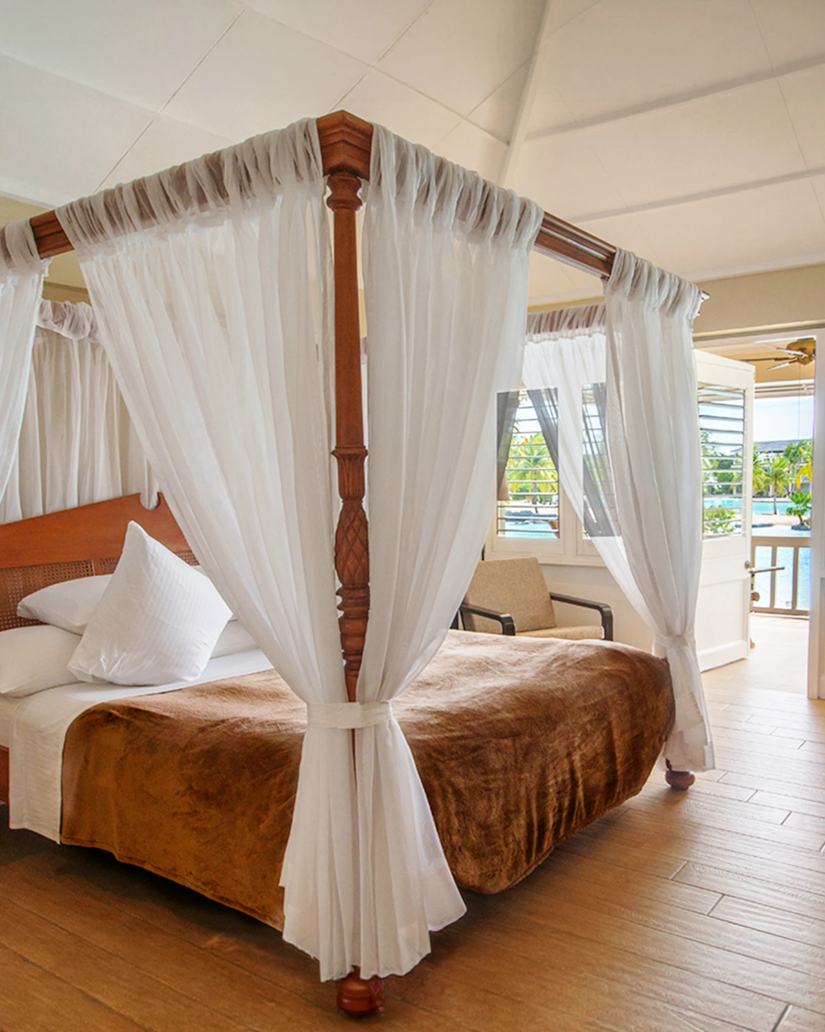 Four-poster king bed with the lagoon just outside the open balcony door