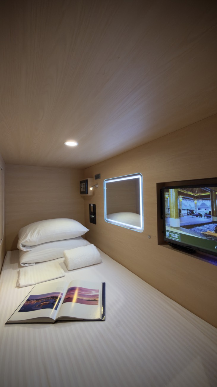 Inside a Youth Pod: bedding, lit vanity mirror, personal safe and TV