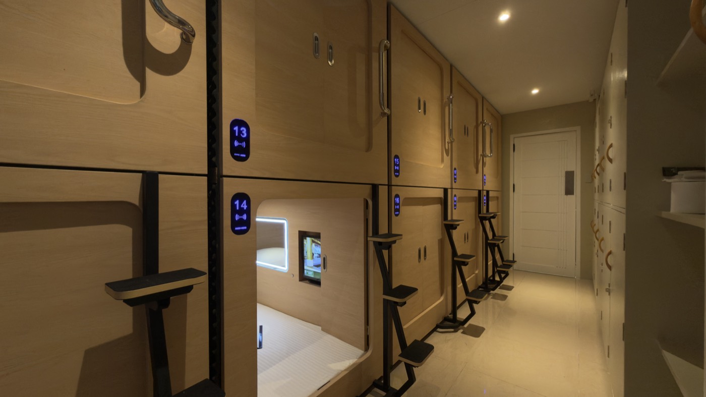 The Youth Pods corridor at night, capsule berths with lit number badges